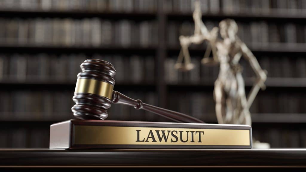 Wooden gavel and nameplate with the word lawsuit in front of legal library background