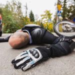 Motorcycle driver without the helmet laying on the road