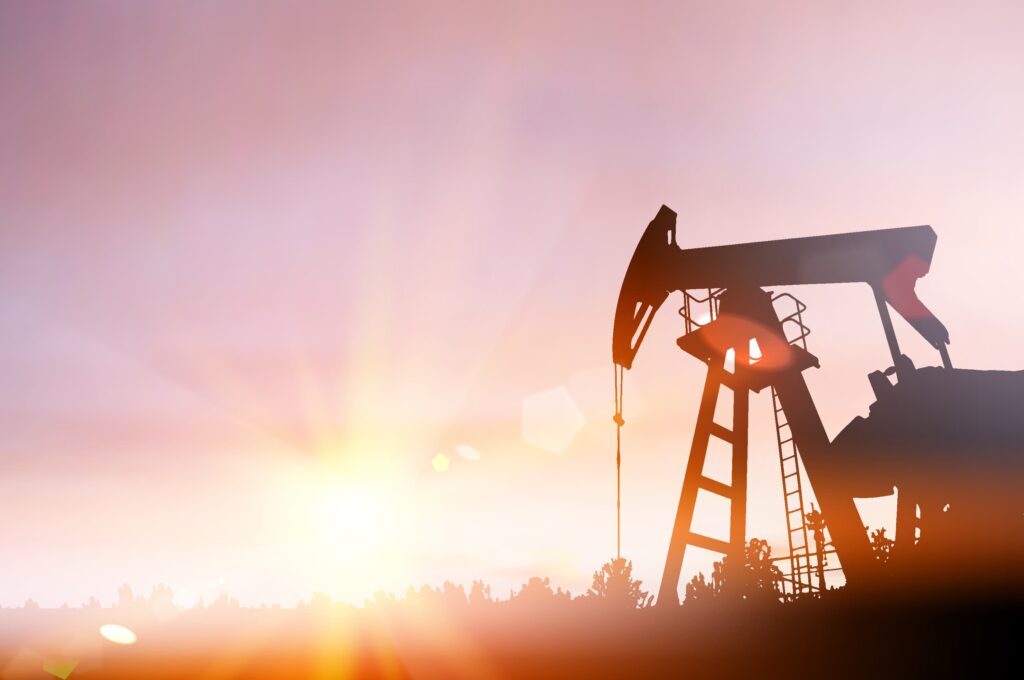 Oil pump jack silhouette extracting crude oil at sunrise with bright sunlight in the background Oil pump jack silhouette extracting crude oil at sunrise with bright sunlight in the background