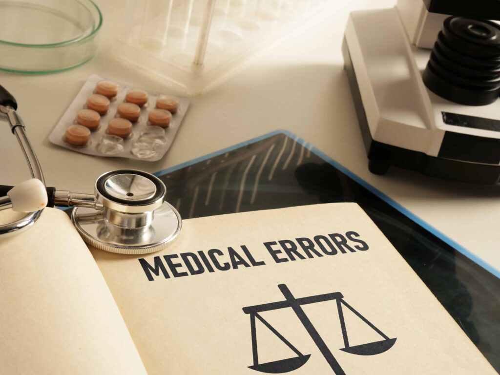 Medical errors concept with stethoscope, pills, and justice scale symbol on legal document.